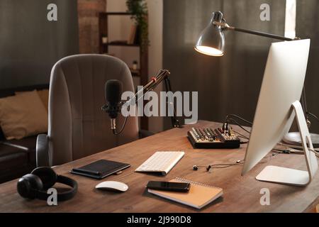 Keine Menschen haben von modernen Vloggern im Loft-Raum mit Computer, Mikrofon und Kopfhörern auf einem Holztisch aufgenommen Stockfoto
