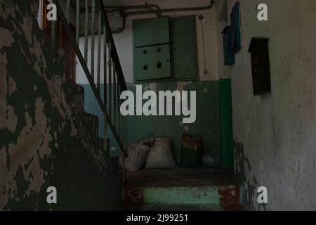 Alte schmutzige Treppe ohne Reparatur mit einer Treppe in einem Wohnhaus in der Ukraine, einem Eingang in einem mehrstöckigen Gebäude Stockfoto