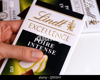 Tambov, Russische Föderation - 29. März 2022 Eine Lindt Excellence Tafel mit intensiver Birne-Schokolade in einer Frauenhand. Eine weitere Schokoladentheke liegt im Hintergrund Stockfoto