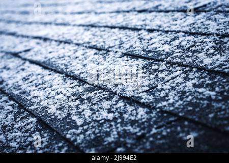 Saisonaler Hintergrund etwas Schnee auf Asphaltschindeln Stockfoto