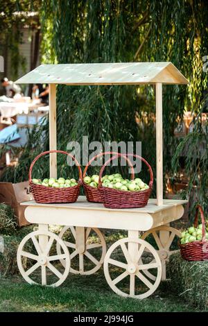 .Holzwagen mit Körben von Äpfeln in der Natur. Stockfoto