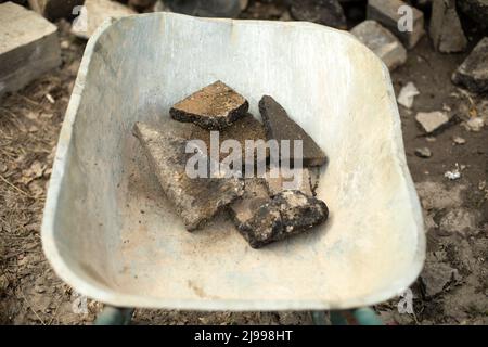 Wagen mit Steinen. Gartenwagen. Reinigung von Bauabfällen. Transport von gebrochenem Asphalt. Baumaterial in Russland. Stockfoto