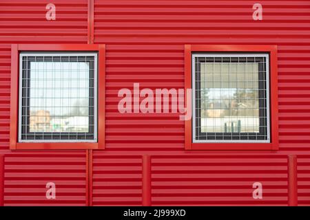 Fenster in roter Wand. Fenster mit Gitter. Details des Gebäudes. Geschützte Wand. Stockfoto