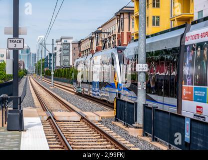 Lynx Blue Line Pendlerzug Richtung Uptown Charlotte, North Carolina, zeigt Hochhäuser, Wohngebäude und Bahngleise. Stockfoto