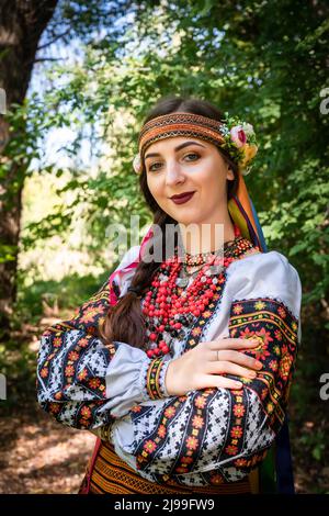 Ukrainisches Mädchen in ukrainischer Nationaltracht steht auf einem Pfad im Wald. Stockfoto