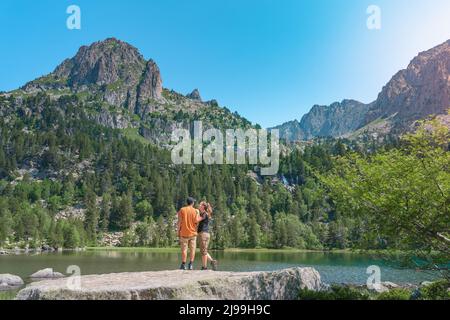 Junges attraktives Paar, das sich im Sommer bei Sonnenuntergang an einem wunderschönen See in den Bergen die Hände hält. Discovery Travel Love Destination Konzept. Stockfoto