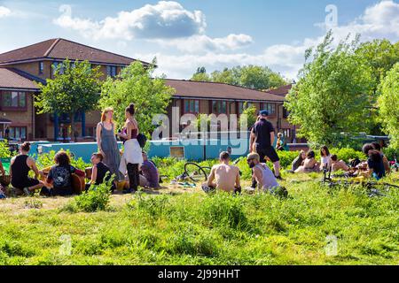 Menschen entspannen sich an einem sonnigen Tag entlang des River Lee Navigationskanals bei Here East, Olympic Park, Stratford, London, Großbritannien Stockfoto