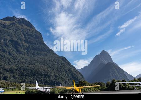 Milford New Zealand,- April 17 2022; kleine Passagierflugzeuge auf dem Boden unter Bergen in Silhouette führt zu berühmten Wahrzeichen, die Touristen anzieht Stockfoto