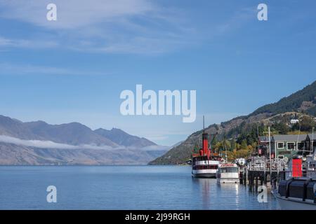 Queenstown Neuseeland - 14 2022. April; Blick vom Lake Wakatipu auf den See und die konvergierenden Berge, vorbei an Steamer Wharf und dem historischen Earnslaw-Schiff. Stockfoto