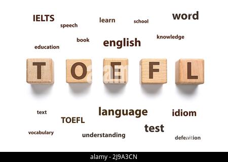 Text TOEFL aus Holzwürfeln und verschiedenen Wörtern auf weißem Hintergrund. Konzept des Englischstudiums Stockfoto