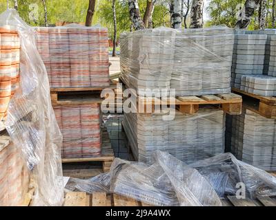 Aus nächster Nähe werden die neuen Pflasterplatten ordentlich auf Paletten gestapelt. Reparatur von Gehwegen und Austausch von Pflasterplatten. Wiederaufbau der Stadt Stockfoto