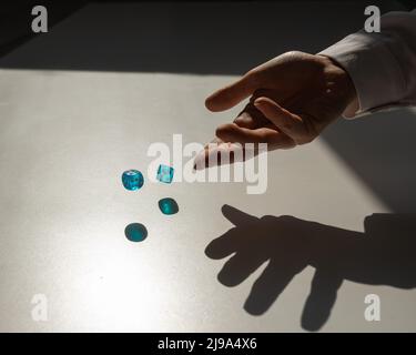 Frau wirft ein Paar blaue transparente Würfel. Stockfoto