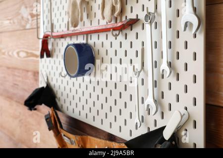 Pegboard mit modernen Werkzeugen auf Holzwand Stockfoto