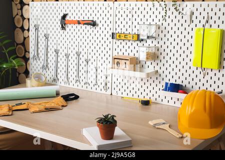 Schreibtisch und Pegboards mit verschiedenen Werkzeugen in der Werkstatt Stockfoto