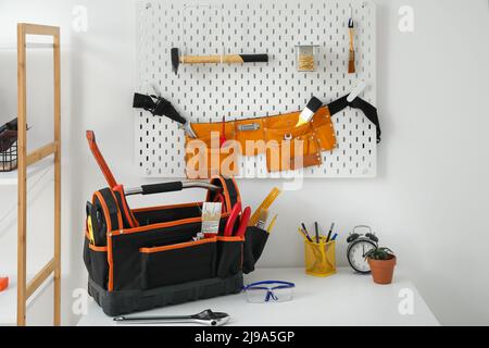 Arbeitsplatz und Pegboard mit verschiedenen Werkzeugen in der Werkstatt Stockfoto