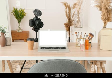 Bloggerarbeitsplatz mit modernem Laptop, Kamera und dekorativer Kosmetik im Studio Stockfoto