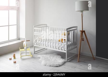 Innenraum des hellen Kindergartens mit Kinderbett, Lampe und Spielzeug Stockfoto