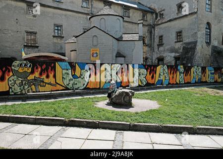 Lviv, Ukraine. 21.. Mai 2022. Eine Frau sitzt vor einem Graffiti-Denkmal für das ukrainische Militär und ihren andauernden Krieg mit Russland. Ein Mühlstein steht im Vordergrund, Russland ist am 24.. Februar 2022 in die Ukraine eingedrungen. (Foto von Joe M O'Brien/SOPA Images/Sipa USA) Quelle: SIPA USA/Alamy Live News Stockfoto