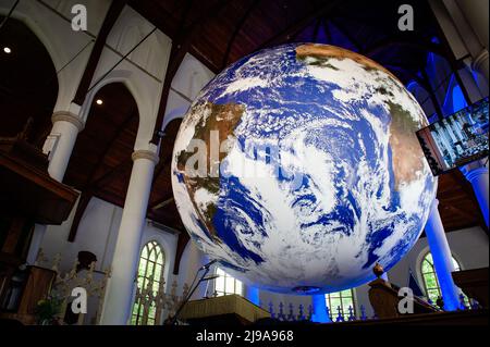 Ein großer Erdball ist in der Mitte einer Kirche platziert. Gaia ist ein tourisches Kunstwerk des britischen Künstlers Luke Jerram. Das Kunstwerk misst sieben Meter im Durchmesser und wurde aus 120dpi detaillierten NASA-Bildern der Erdoberfläche erstellt. Es bietet die Möglichkeit, unseren Planeten in drei Dimensionen zu sehen. Diese Erfahrung gibt den Menschen ein Gefühl von Ehrfurcht, eine tiefe Erkenntnis der Verbundenheit des Lebens auf der Erde. In der griechischen Mythologie ist Gaia die Personifizierung von Mutter Erde. Dieses Kunstwerk gehört zu Arcadia, einem 100-tägigen Kulturprogramm, das diesen Sommer in der Provinz Friesland, der Nether, stattfindet Stockfoto