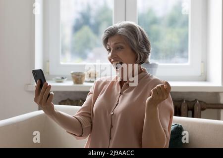 Glücklich überrascht Senior Smartphone-Nutzer Frau Blick auf Handy Stockfoto