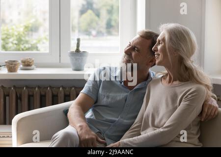 Glücklich verträumt reifes Paar umarmt auf heimisch Couch mit Liebe Stockfoto