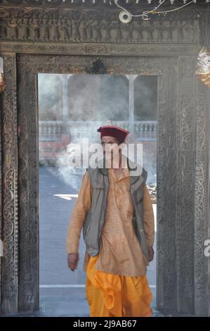 Mandi, Himachal Pradesh, Indien - 10 16 2021: Vorderansicht eines Pujari (Priester), der himachali topi (Mütze) und dhoti trägt, der seitlich schaut, während er durch die Tempeltür geht Stockfoto