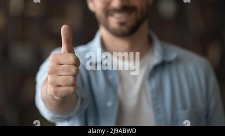 Nahaufnahme eines lächelnden, tausendjährigen Mannes, der den Daumen hoch hält Stockfoto