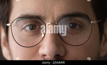 Beschnittenes Porträt eines jungen Mannes, der eine Brille trägt und die Kamera anschaut Stockfoto