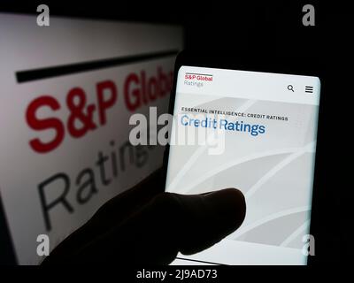 Person, die Mobiltelefon mit der Webseite des US-Finanzdienstleisters SP Global Inc auf dem Bildschirm vor dem Logo hält. Konzentrieren Sie sich auf die Mitte des Telefondisplays. Stockfoto