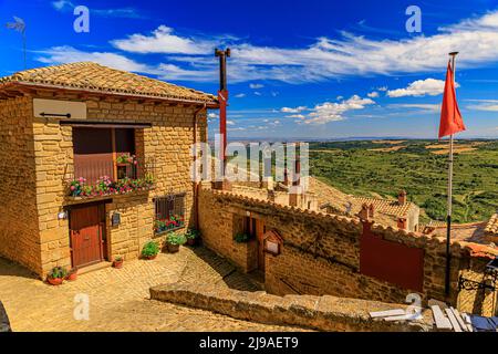 Luftaufnahme von alten Steinhäusern und terrassenförmigen Feldern, die ein Tal bei der Festungskirche Iglesia de Santa Maria in Ujue, Navarra, Spanien umgeben Stockfoto