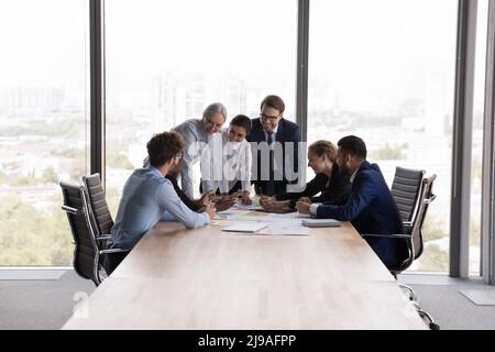 Ältere und junge Teamkollegen versammelten sich im Sitzungssaal bei der Unternehmensbesprechung Stockfoto