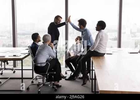 Zwei Kollegen gaben während des Briefings im modernen Sitzungssaal fünf hoch Stockfoto