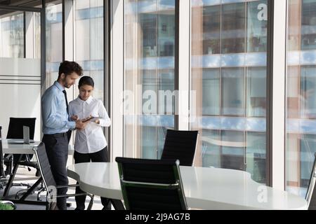 Multiethnische Kollegen, die digitale Tablets verwenden, diskutieren über neue Anwendungen Stockfoto