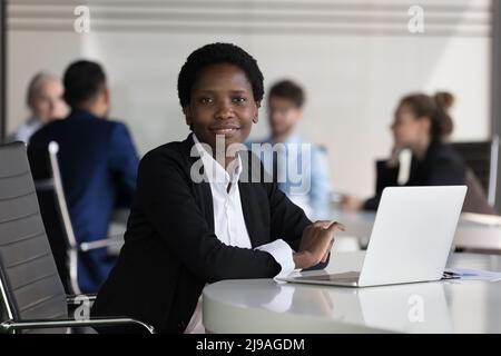 Erfolgreiche afrikanische Geschäftsfrau posiert sitzen am Schreibtisch im Büro Stockfoto