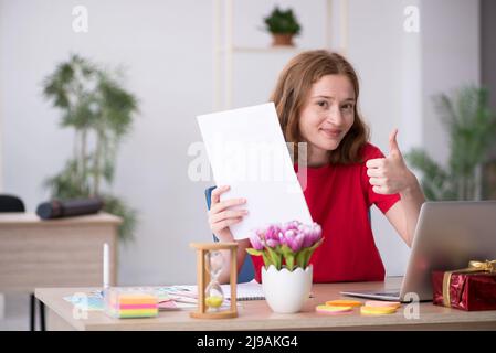 Junge Designerin feiert Weihnachten am Arbeitsplatz Stockfoto