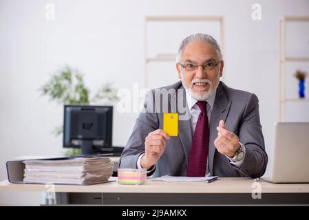 Ein alter Geschäftsmann mit Kreditkarte am Arbeitsplatz Stockfoto