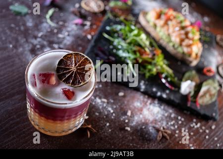 Frischer, stilvoller, rosafarbener Grapefruit-Cocktail mit Schaumstoff und Sandwich Stockfoto