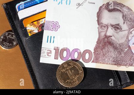 Schwarzes Leder-Etui mit Geld. 1000 Hryven Banknote Nahaufnahme. Krise, Ertrag, Wachstum, Verlust, Diebstahl Entdeckung Stockfoto