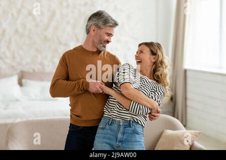 Fröhliches Paar Mittleren Alters, Das Im Modernen Schlafzimmer Zu Hause Tanzt Stockfoto