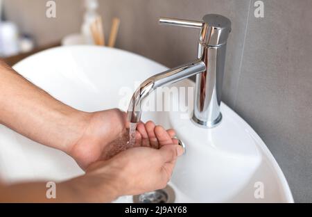 Nahaufnahme eines Mannes, der sich im Badezimmer die Hände wusch Stockfoto