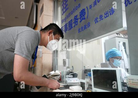 (220522) -- PEKING, 22. Mai 2022 (Xinhua) -- Mei Xiaodong (L) meldet sich in einem medizinischen Versorgungszentrum der Gemeinde an, um von Bewohnern unter Quarantäne im Chaoyang Bezirk in Peking, der Hauptstadt Chinas, Medikamente zu kaufen, die von Bewohnern unter häuslicher Quarantäne angeordnet wurden, 21. Mai 2022. Mei Xiaodong, 35, ist Regierungsangestellter des Bezirks Chaoyang in Peking. Mei wurde entsandt, um sich der Arbeit des Frontpersonals in einer Gemeinde im Kampf gegen COVID-19 anzuschließen und den Bewohnern unter Quarantäne zu helfen, Medikamente für chronische Krankheiten zu kaufen. Gemeindearbeiter, Ärzte und Freiwillige übernehmen die Verantwortung für die Bewertung, den Einkauf und das Deli Stockfoto