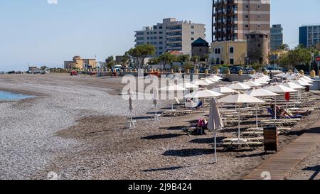 Rhodos, Griechenland Leere Liegen und geschlossene Sonnenschirme am Strand in Griechenland. Stockfoto