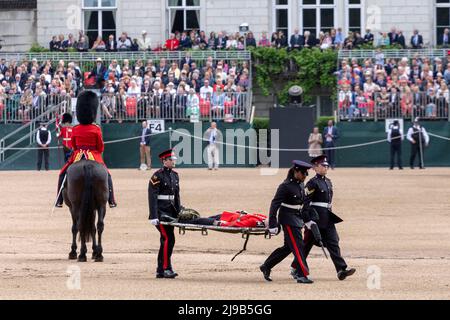 Ein Mitglied der Irischen Garde, das heute während der Überprüfung des Generalmajors über das Trooping the Color bei der Horse Guards Parade unter der hohen Temperatur ohnmächtig wird Stockfoto
