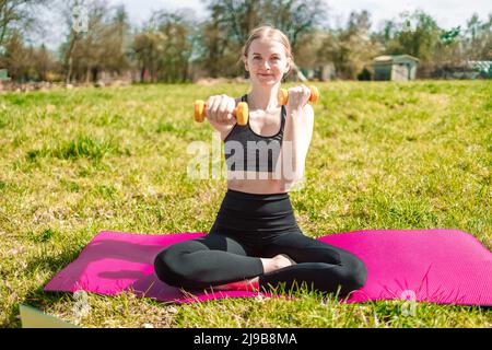 Junge schöne fit Frau in Sportbekleidung Training mit Hanteln tun Fitness-Aktivität im Sommerpark Stockfoto