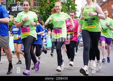 Freya Lewis (Mitte) trifft auf mehr als 20.000 Fahrer beim Great Manchester Run durch das Stadtzentrum von Manchester, um den fünfjährigen Jahrestag des Bombenanschlags in der Manchester Arena zu feiern. Frau Lewis, 19, die nach mehreren Verletzungen, Brüchen und Verbrennungen beim Bombenanschlag wieder gehen lernte, wird für die Royal Manchester Children's Hospital Charity Rennen, die ihr das Leben rettete. Bilddatum: Sonntag, 22. Mai 2022. Stockfoto