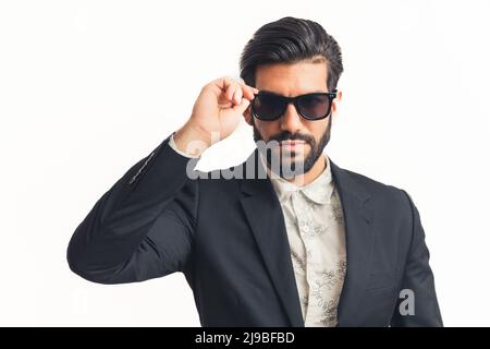 Porträt eines jungen Geschäftsmannes, der seine neue Sonnenbrille auf einer weißen, horizontal solierten Rückensohle aufsetzt. Hochwertige Fotos Stockfoto