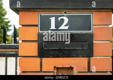 Hausnummer 12 über Briefkasten im Zaun, Nahaufnahme Stockfoto