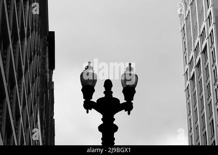 Städtische Straßenlaterne, die zwischen zwei Wolkenkratzern im Stadtzentrum steht. Stockfoto