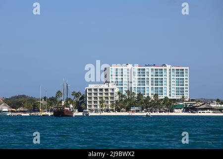 PALM BEACH, ARUBA - 17. OKTOBER 2021: Blick vom Meer des Hotel Radisson Blu, in den vorderen Gebäuden des Holiday Inn Resort und Ausflugsboote auf Aruba Stockfoto