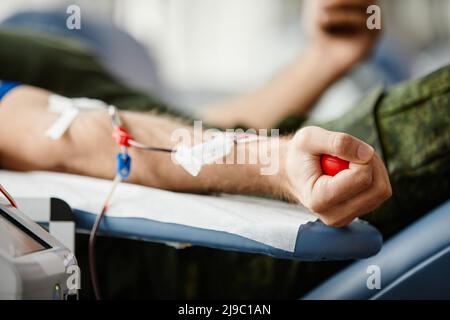 Nahaufnahme des männlichen Spenders, der Blut spendet und den roten Stressball in der Hand am Spendenzentrum hält, Platz kopieren Stockfoto